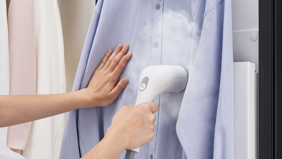 A woman using the handheld steamer on a shirt