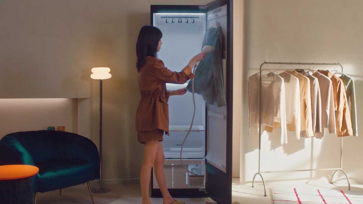 A woman steaming a garment inside the door of the LG Styler