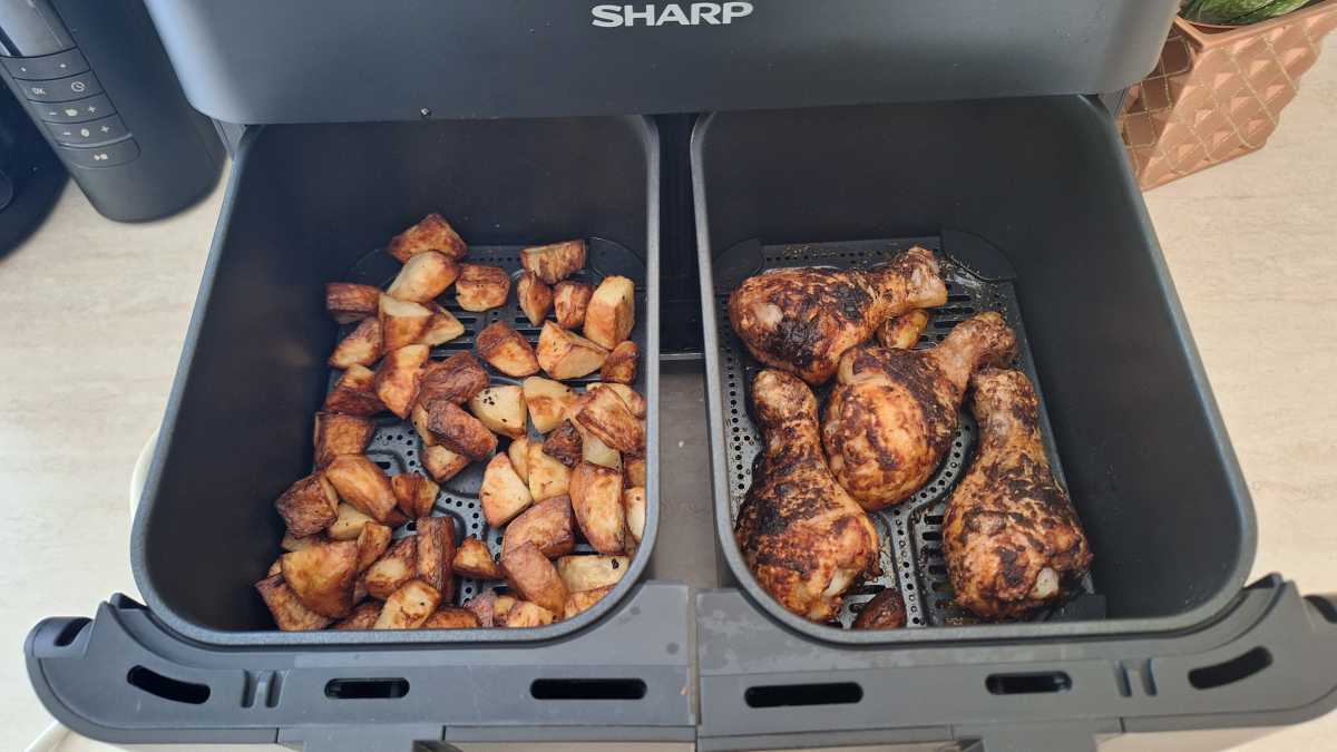 Una vista de patatas y muslos de pollo cocinados en dos cajones separados en la freidora de aire digital Sharp de 8 litros con cajón doble y acabado sincronizado