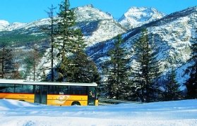 Foto del autobús postal suizo viajando por la campiña suiza con un fondo montañoso