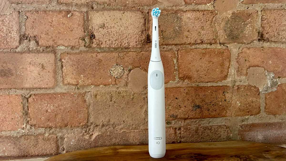 Oral-B iO2 de pie contra una pared de ladrillos